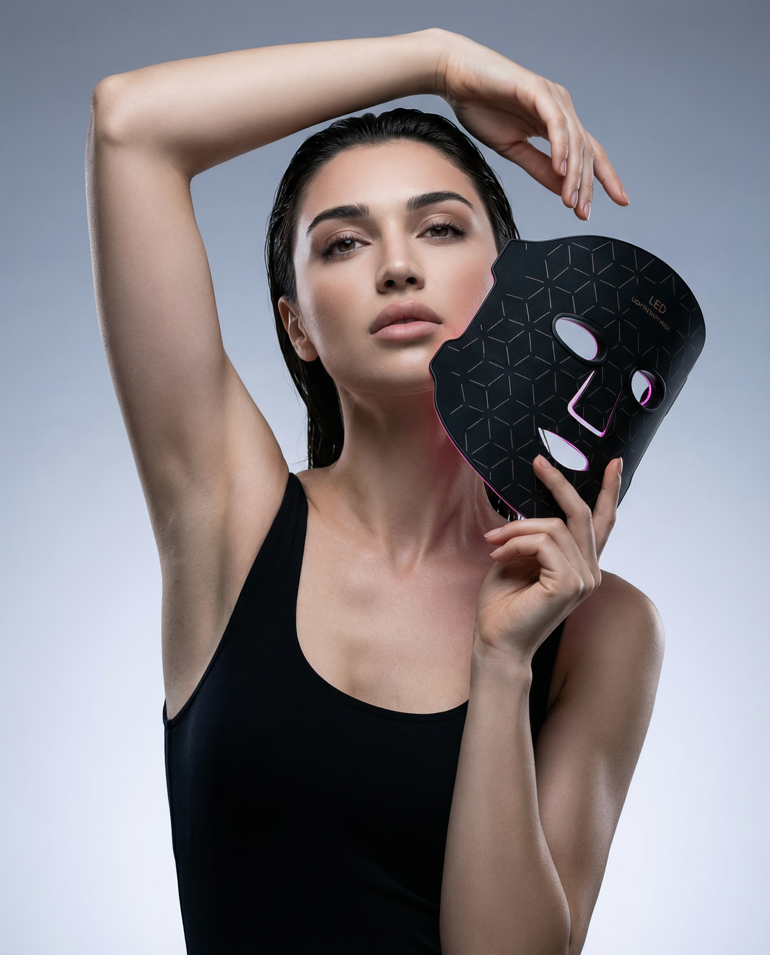 Woman holding a black facial mask against a gray background
