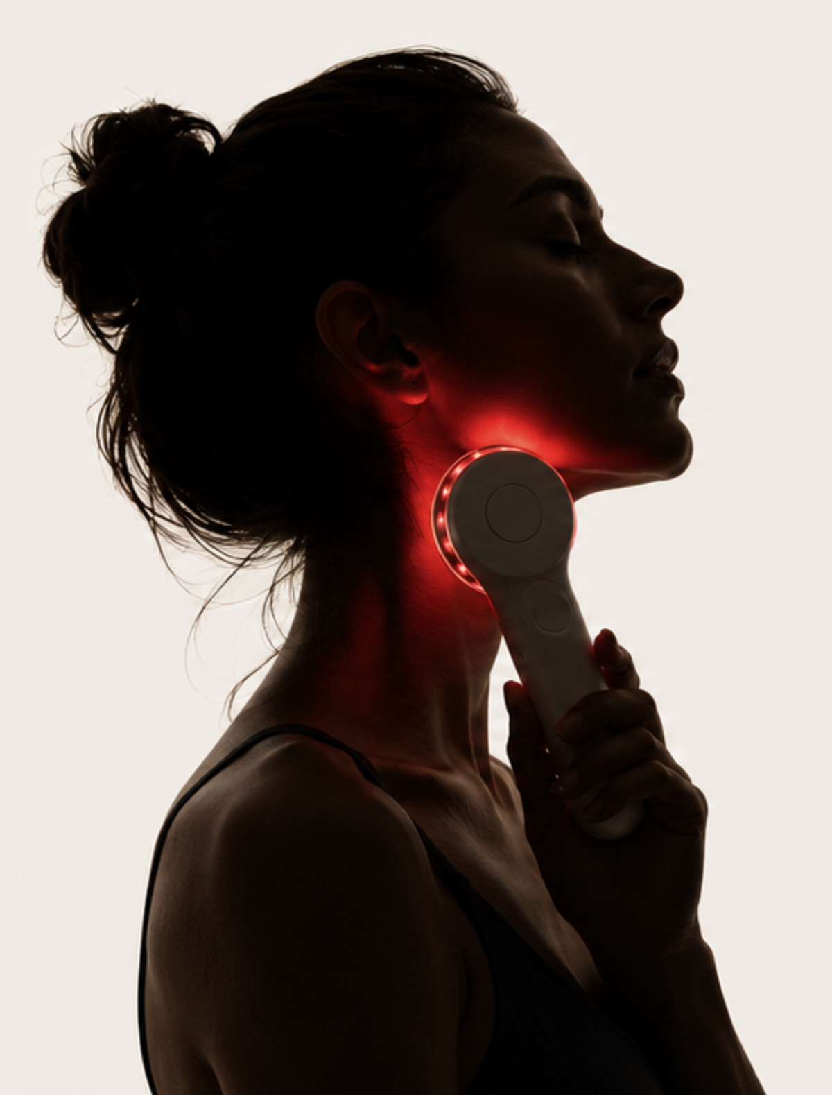 Woman using a red LED light therapy device on her neck to support firmer-looking skin and reduce the appearance of fine lines.